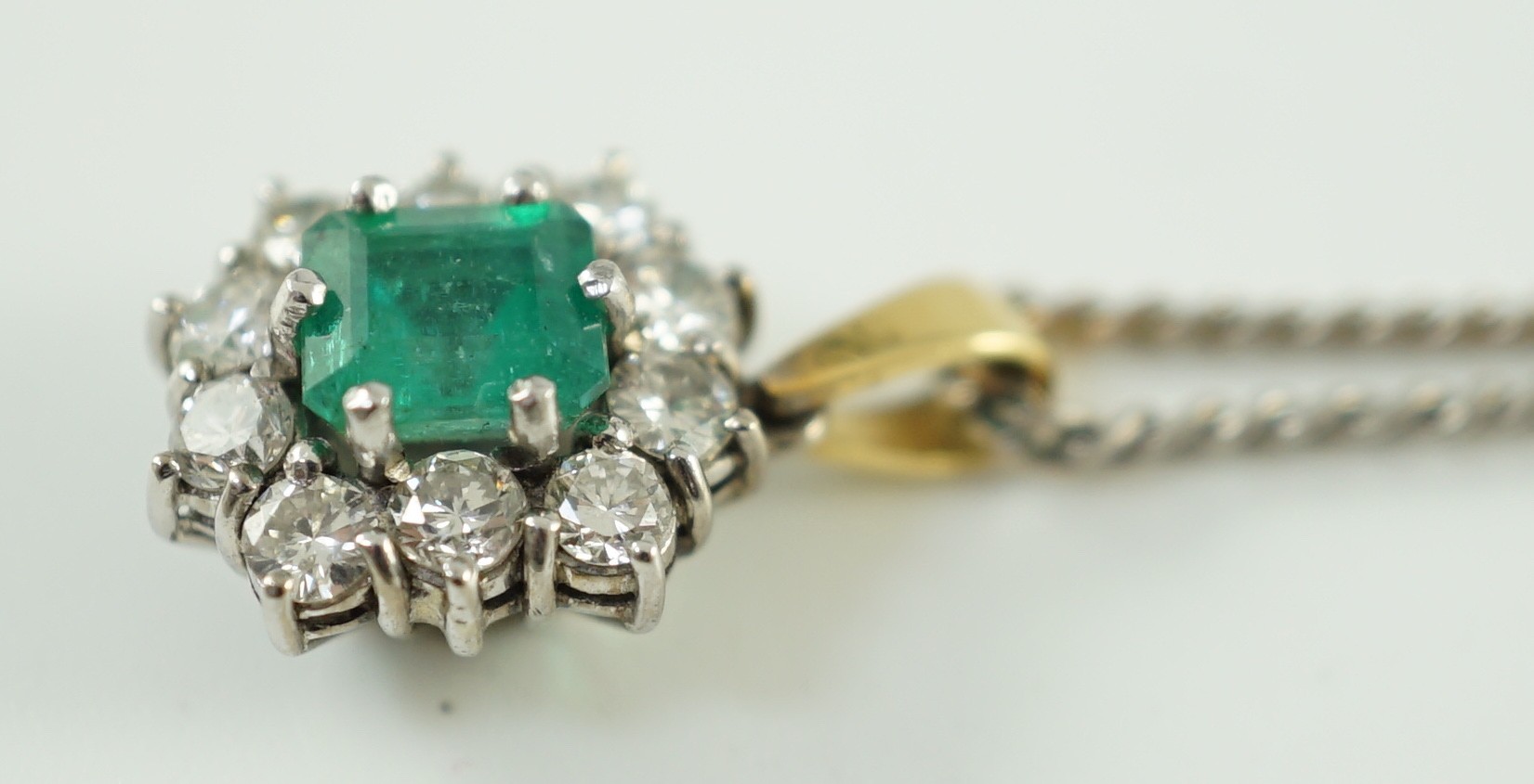 An 18ct white and yellow gold, emerald and diamond set shaped rectangular cluster pendant, on a 9ct white gold chain